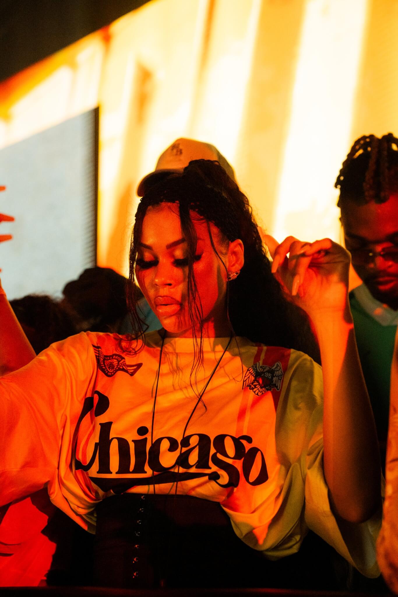 Woman focused on dancing in a crowd, lit by warm yellow and orange stage lights
